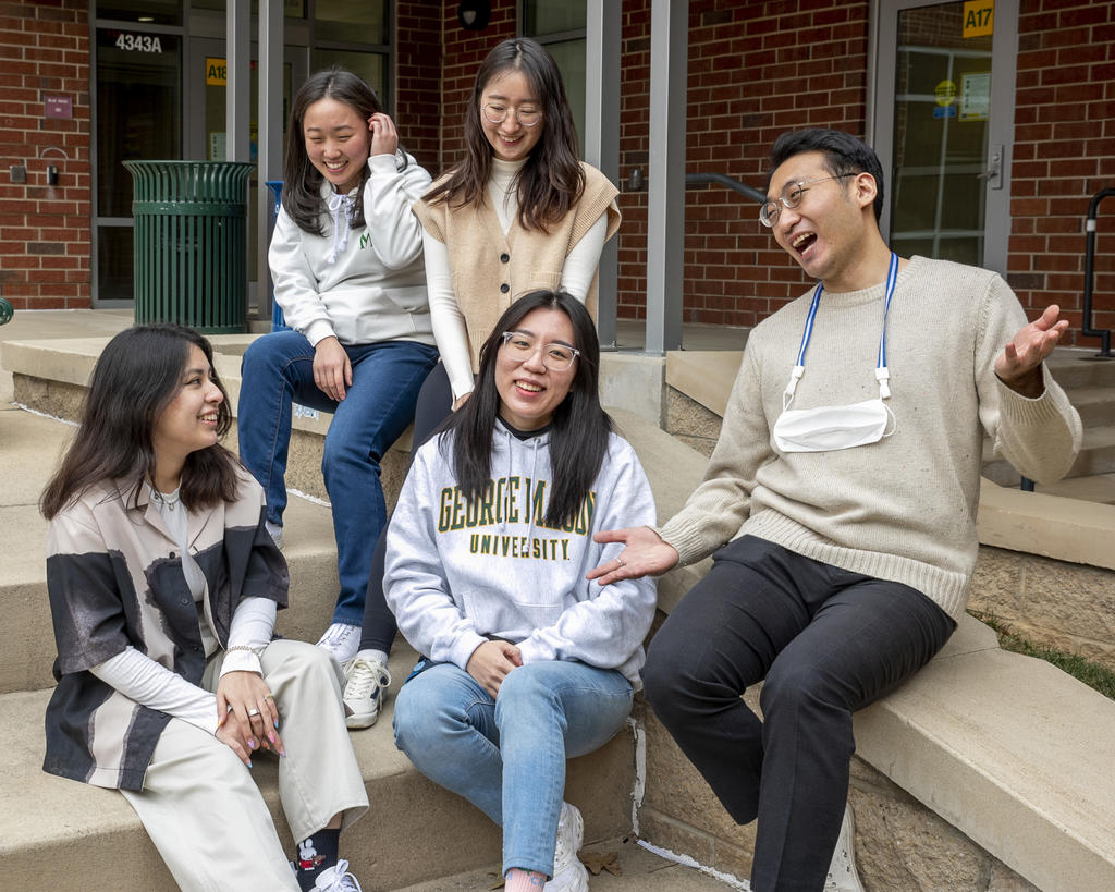Five Mason Korea students talk on steps outside a university building.